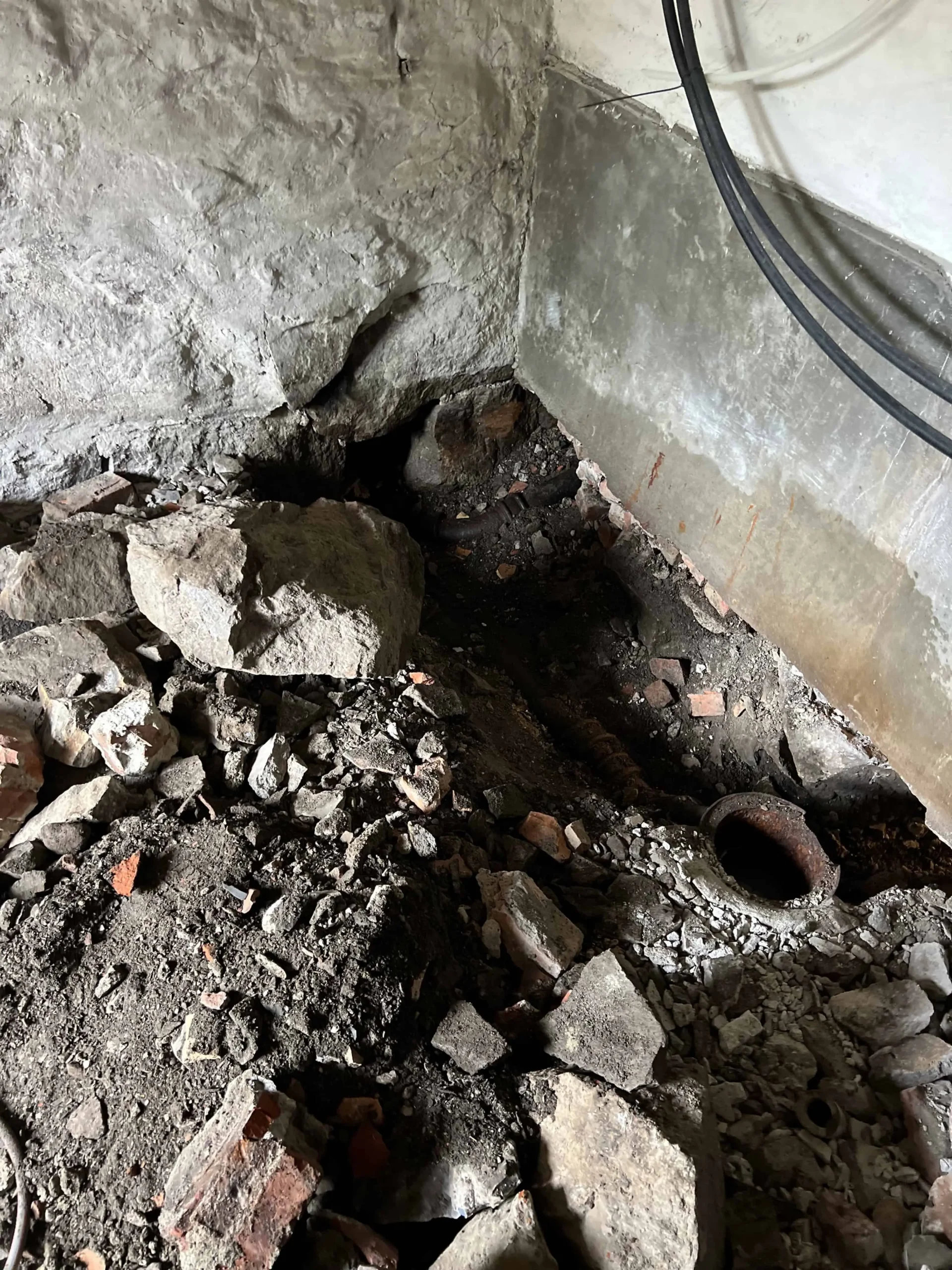 Rørlegging under oppussing, synlig avløpsrør i kjeller med grus og murstein.