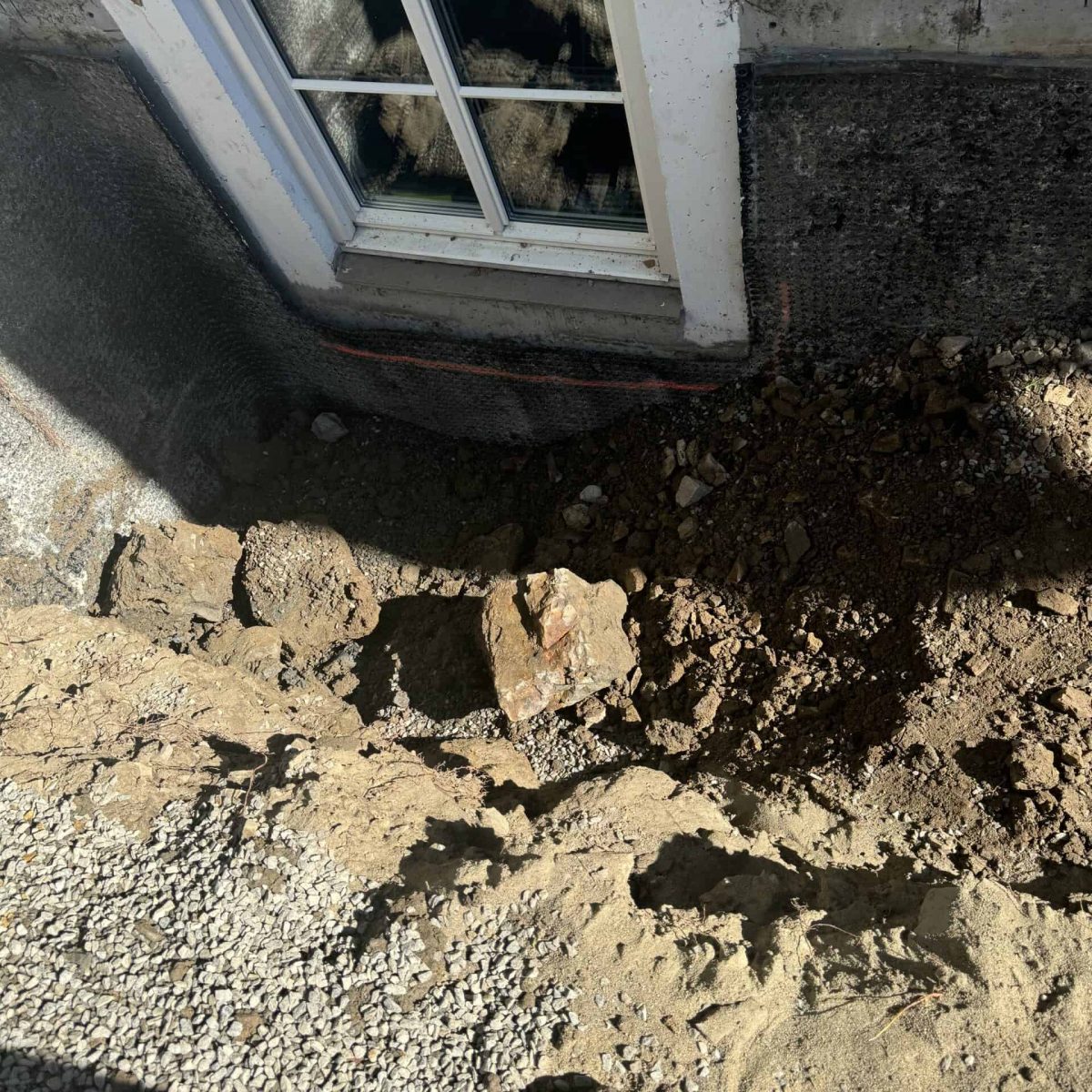 Fasade med grunnarbeid og isolasjon rundt vindu på byggeplass. Effektivt isolasjonsarbeid for energibesparelse og byggkvalitet.