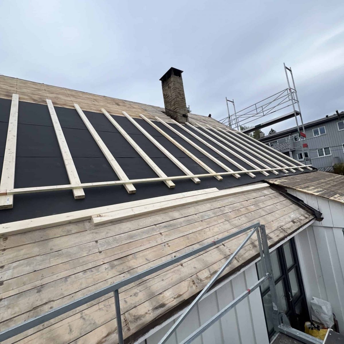 Byggproffene - Sommerarbeid på tak med oppføring av trekonstruksjon og isolasjonsarbeid. Erfaren byggentreprenør for moderne takrenoveringer.