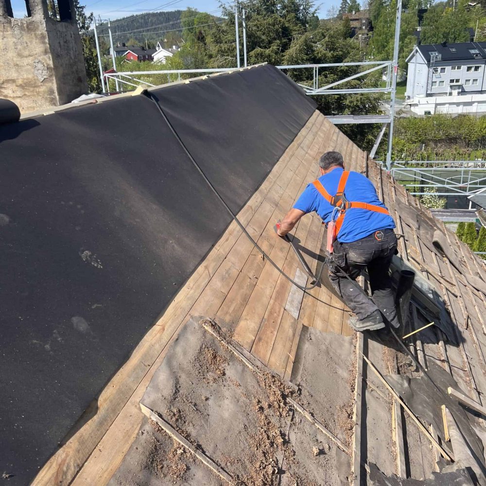 Profesjonell taktekker legger shingel på boligtak, sikrer holdbarhet og beskyttelse mot vær og vind.